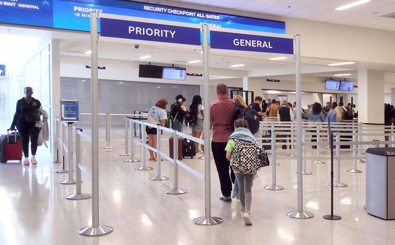 Overhead signs on tall partition posts direct passengers into the security queue at Dallas Fort Worth International Airport.
