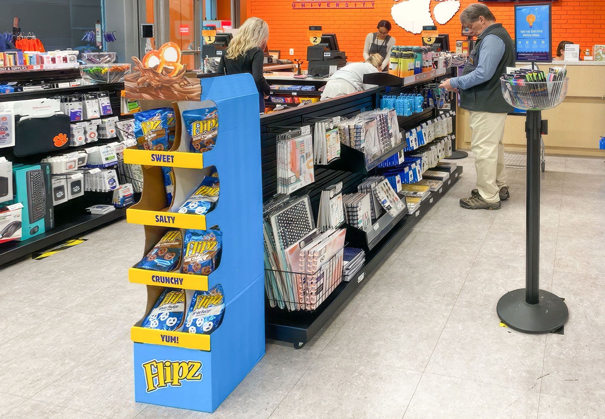 Beltrac retractable belt stanchions and NeXtrac slatwall gondolas merchandise the checkout queue at the Clemson University bookstore.