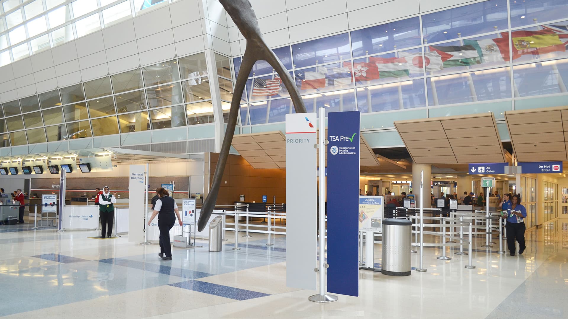 Banner signs on tall partition posts guide passengers through the terminal at Dallas Fort Worth International Airport.