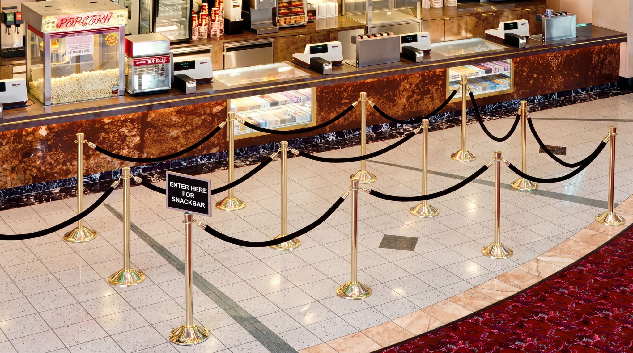 Traditional post and rope stanchions guide moviegoers through the concession queue at a movie theater.