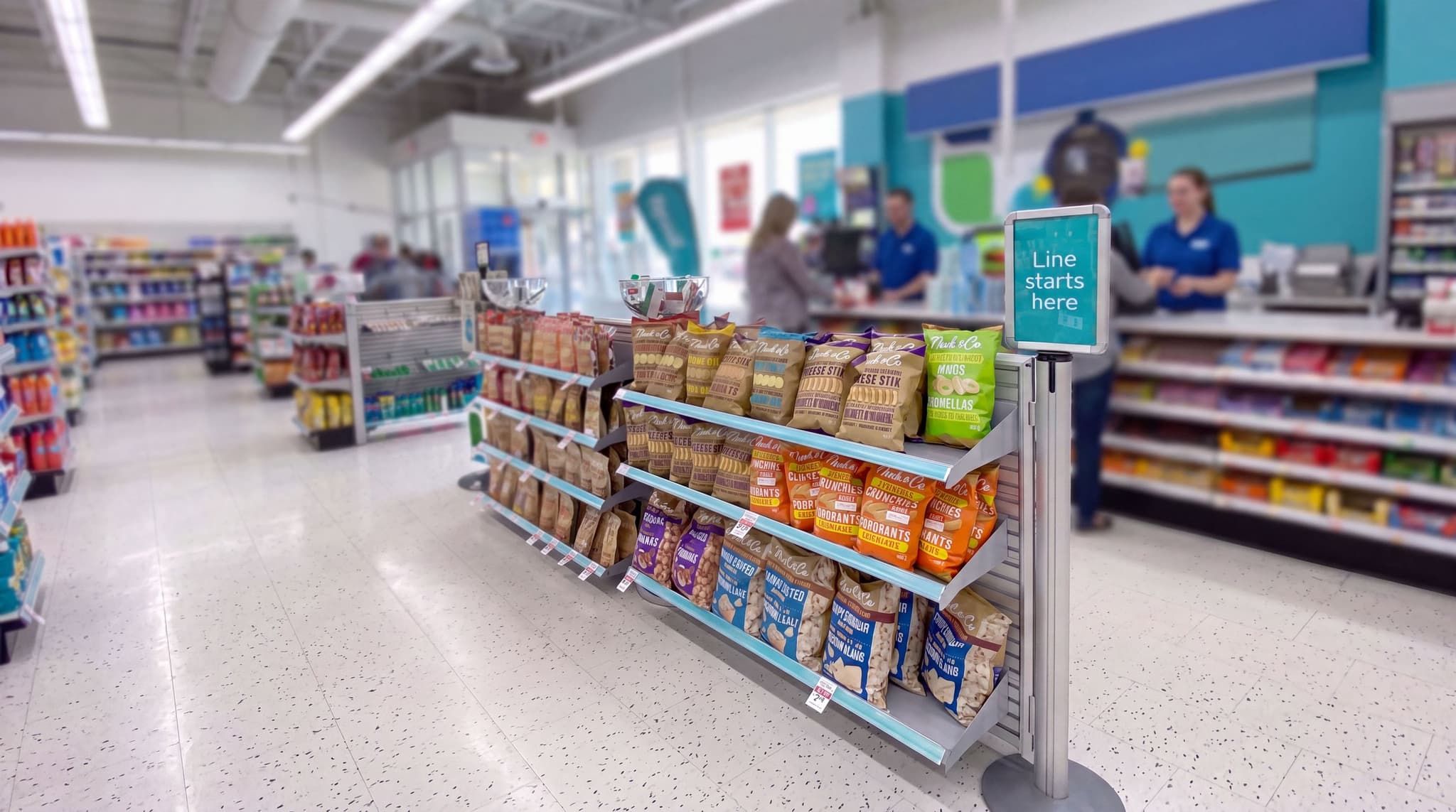 Beltrac retractable belt stanchions and NeXtrac slatwall shelving merchandise the checkout queue at a Rexall drugstore.