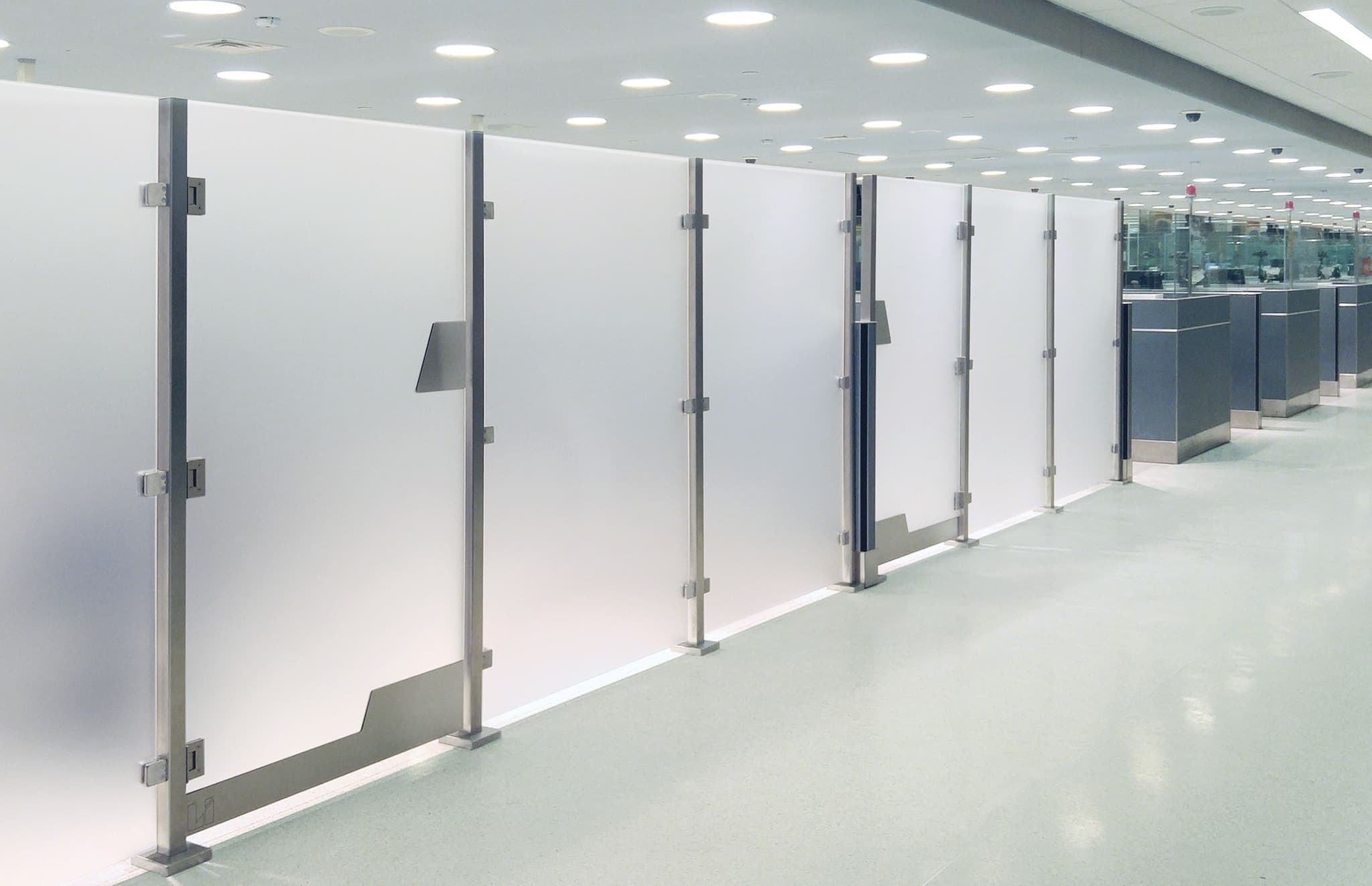 A tall Architectural Partition Wall with access gates divides the passenger area at Dallas Fort Worth International Airport.