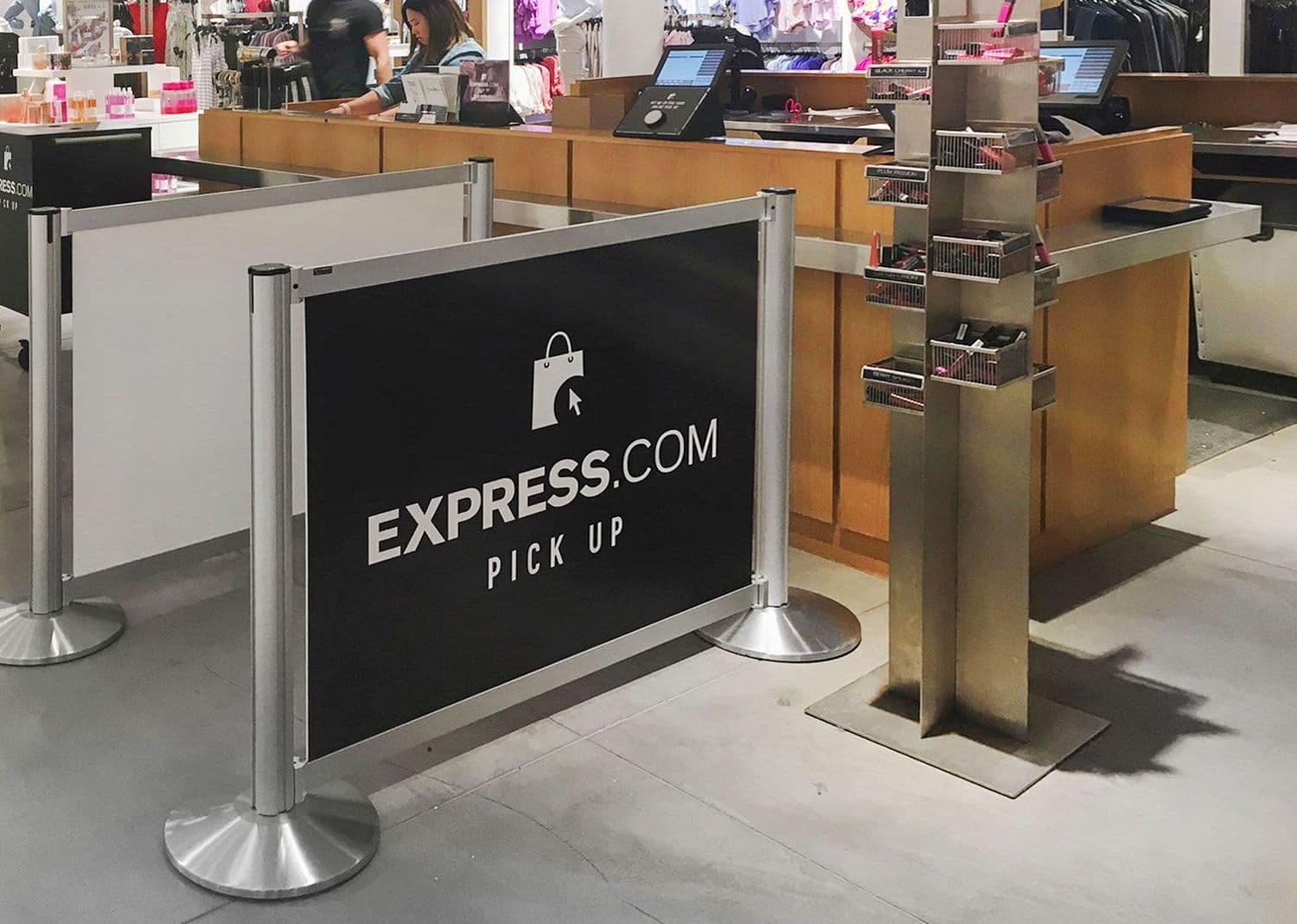 Partition posts with Rigid Rail barriers and printed signage form the online order pickup queue at an Express store.