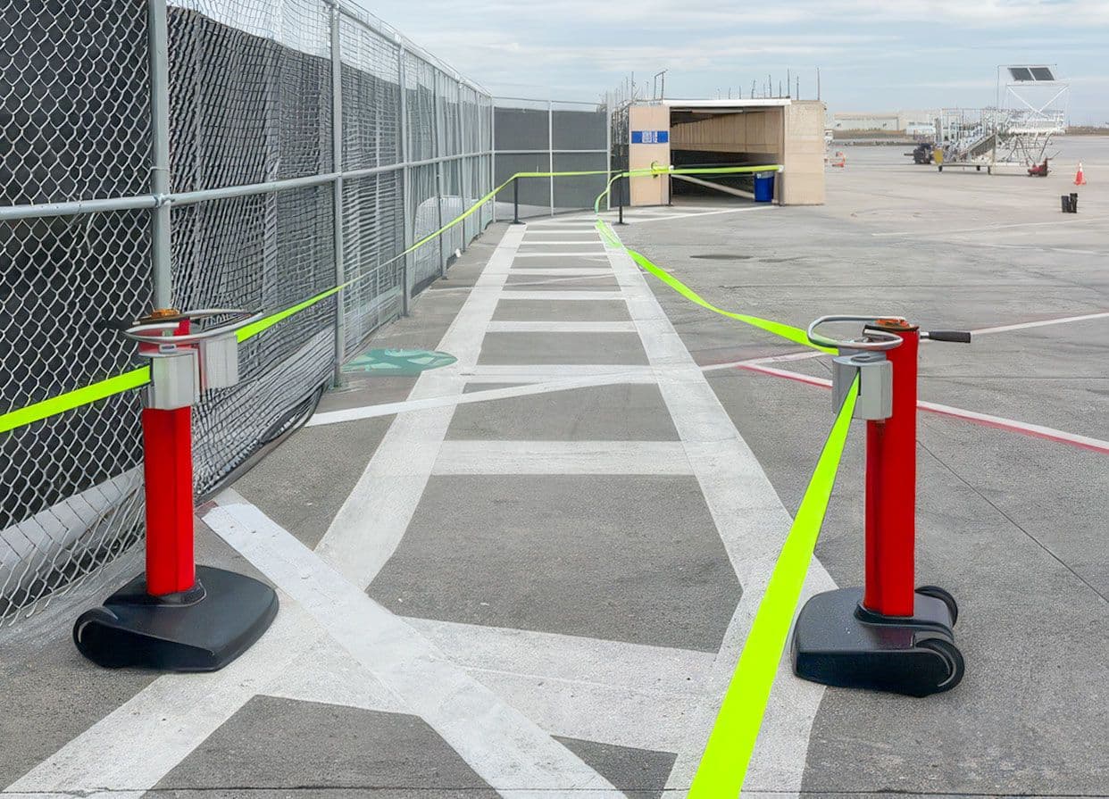 A JetTrac mobile belt barrier forms an outdoor boarding queue on the apron at Savannah Hilton Head International Airport.