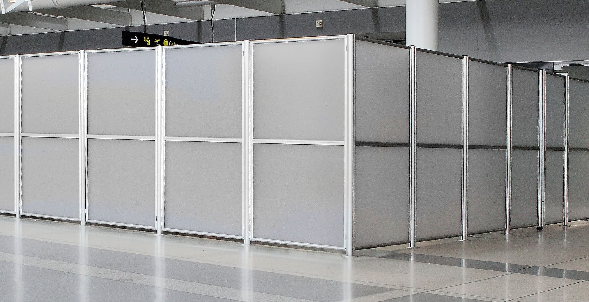 Tall hinged panel barriers with frosted acrylic infill form a wall around a secure area at Toronto Pearson International Airport.