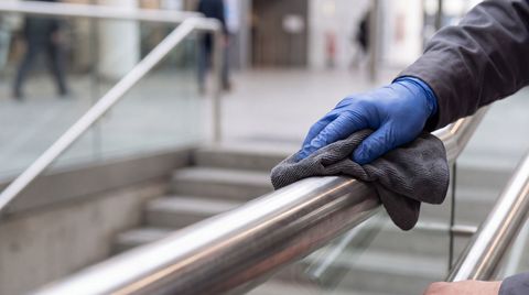 A gloved hand polishing and maintaining a stainless steel handral