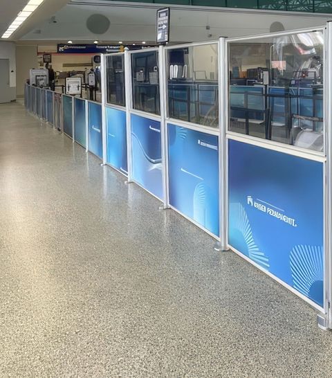 Post and Panel barriers with printed lower panels and clear acrylic above line the security queue at Oakland International Airport.