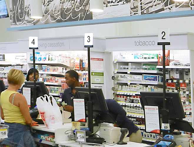 A row of Lavi register lights in a pharmacy, with a customer and employees interacting.