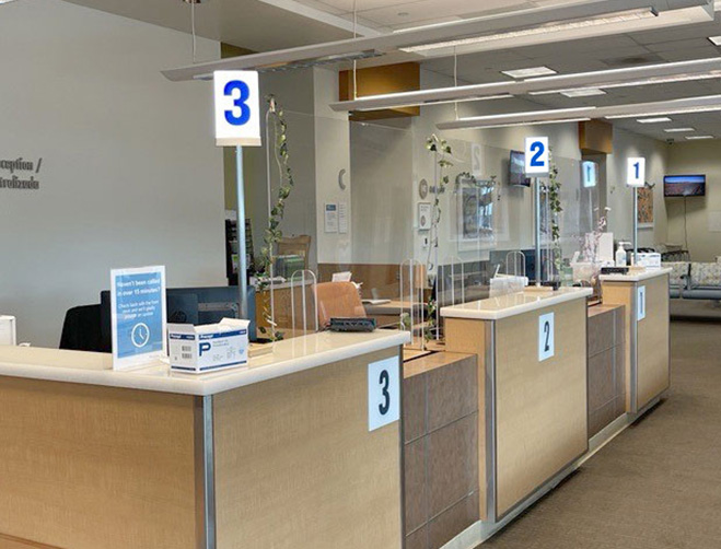 An unattended row of cashier stations, with register lights, in a Kaiser Permanente lobby.